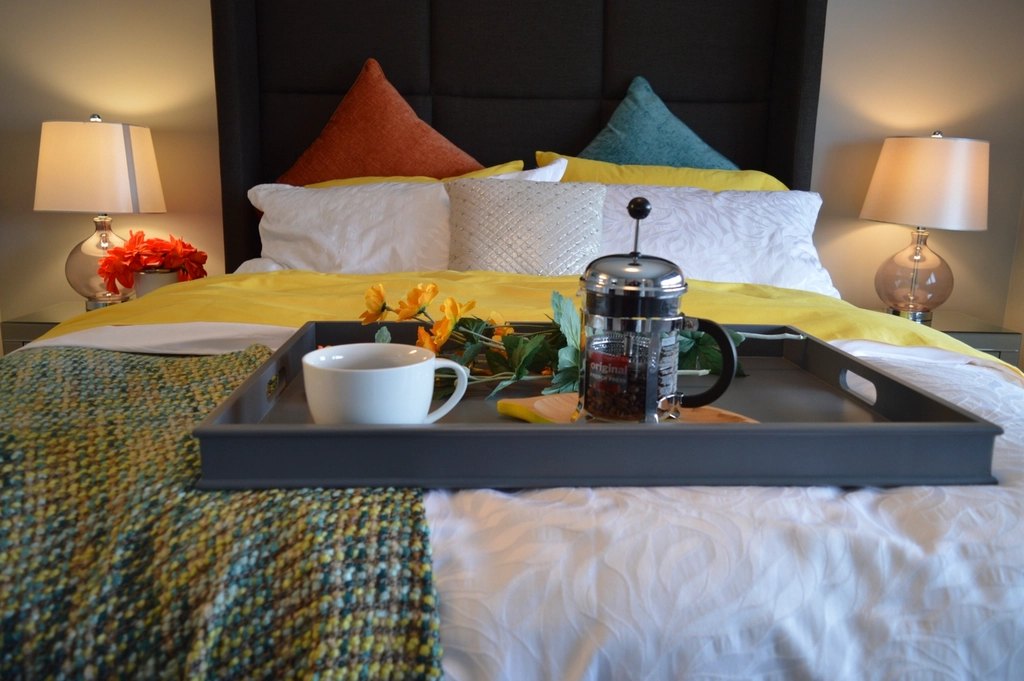 Premium upholstered divan bed with dark panel headboard and bedside lamps