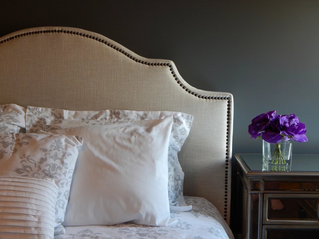 Close-up of a cream upholstered divan bed headboard and soft furnishings